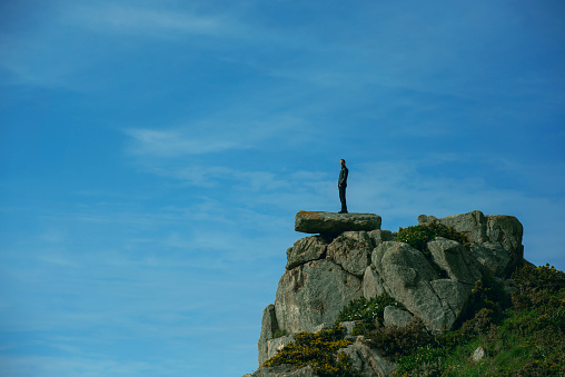 Low angle view and profile view of man standing on the edge of cliff on the French coastline looking and admiring the view