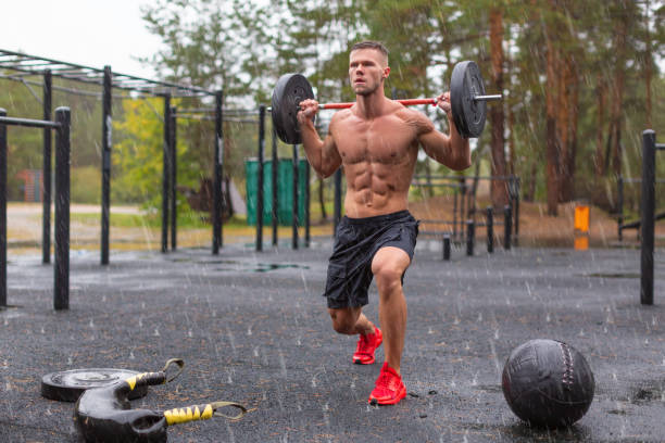Full length photo of a man doing exercise lunges outdoors on a rainy day Full length photo of a man doing exercise lunges outdoors on a rainy day. Outdoor workout under rain. bodybuilder lunge 