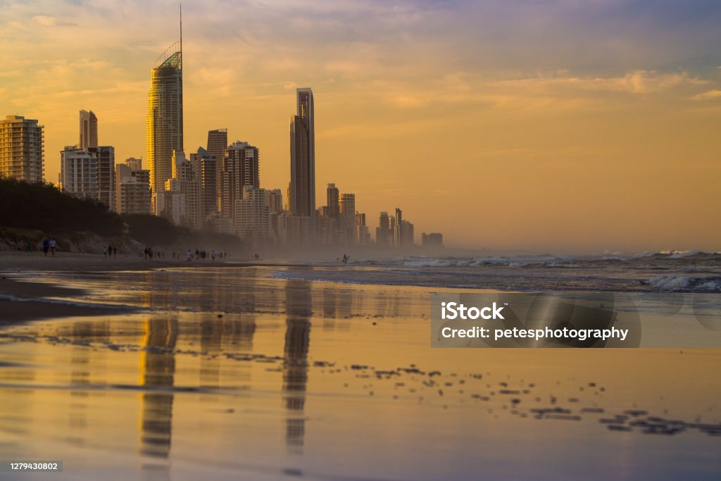 Gold Coast sunrise reflections Looking towards Surfers Paradise, Gold Coast QLD at sunrise from the beach. The tall buildings are reflecting on the water over the sand with a peaceful tranquil feeling. Beach Stock Photo