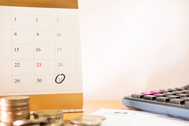 istock Selective focus at the last day reminder of the month on calendar. With blurred coins stack and calculator, tax submission form. Tax or expense due date or payment day concept with white copy space. 1279436686