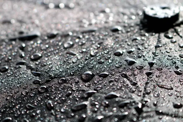 Rain water droplets on black fiber waterproof fabric. Black background