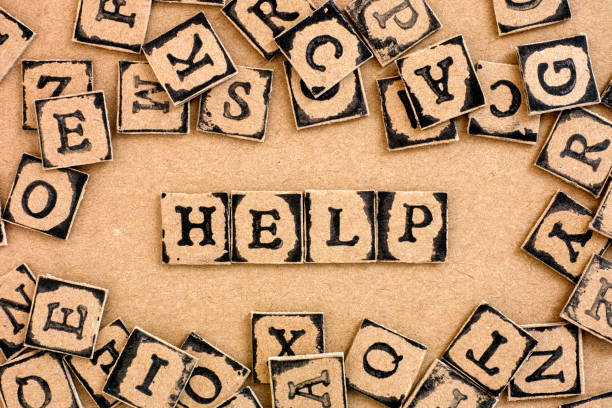 istock Word Help spelled out from cardboard letters made by black alphabet stamps. 1279444382