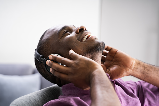 Happy African American Man Enjoying Music Through Headphones In At Home