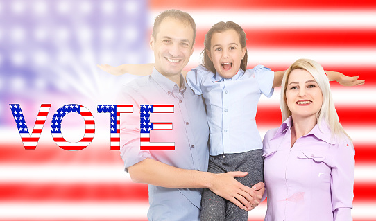 Proud American family waling together holding hands with USA flag blowing in the distance. family vote
