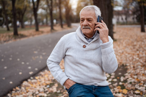 istock Smiling senior man talking on mobile phone in autumn park 1279448325