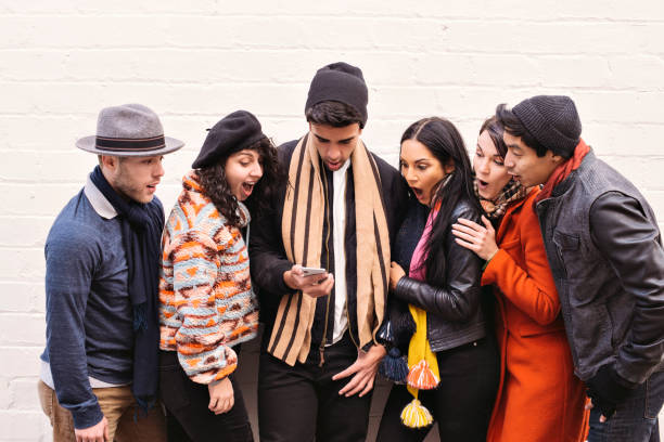 istock Group of Millennials gather around a smart phone and have a shocked expression - Adullts - Surprise - Urban 1279449454
