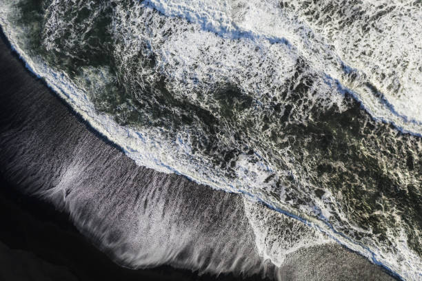 istock Abstract stacks of waves on black sand beach, top down view. 1279450602
