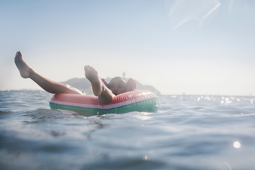 Asian boy swimming in the sea with float.