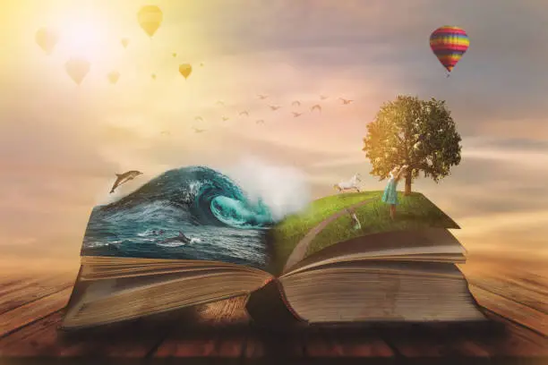 Photo of Concept of an open magic book; open pages with water and land and small child. Fantasy, nature or learning concept, with copy space