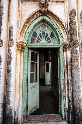 Jamnagar, Gujarat, India - December 2018: An old, elegant arched doorway with open wooden doors inside the ancient Mandvi Tower mosque.