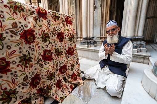 Jamnagar, Gujarat, India - December 2018: An elderly Indian Muslim man praying inside the Mandvi Tower mosque.