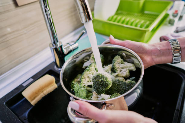 istock Unrecognizable woman washing broccoli over a kitchen sink in a pot 1279465098