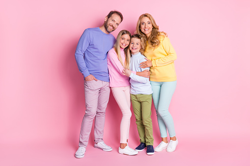 Full size photo of positive family dad hug mom and two kids boy, girl isolated over pink color background