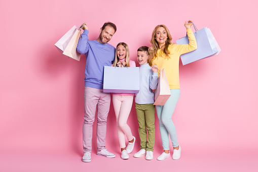 Full size photo of dream amazed family daddy, mommy hold shopping bags isolated over pink pastel color background