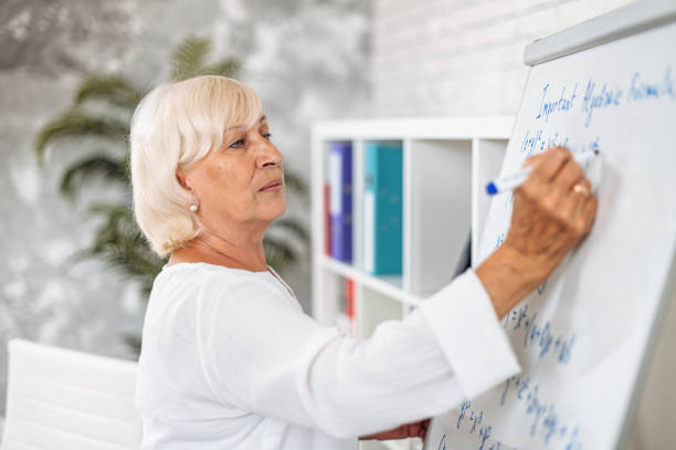istock Senior female teacher writes on a flipchart 1279467503