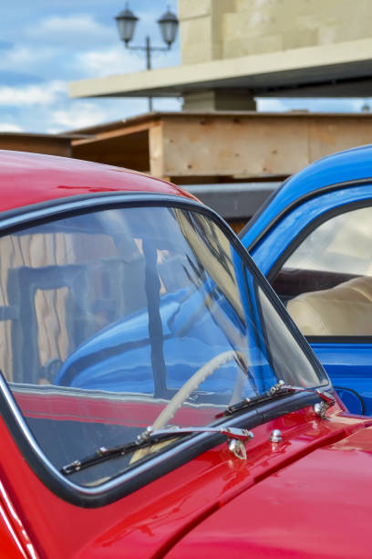kaptur samochodu i przednia szyba czerwonego samochodu na tle niebieskiego samochodu z bliska - hood car headlight bumper zdjęcia i obrazy z banku zdjęć
