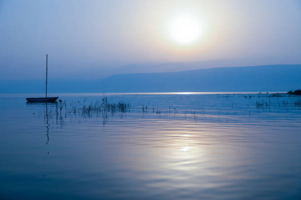 Sunrise over the lake. Boat floating on the calm water under amazing sunset. Boat floating on the calm water under amazing sunset. Sunrise over the lake. galilee photos stock pictures, royalty-free photos & images