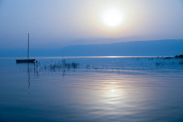 nascer do sol sobre o lago. barco flutuando na água calma sob o pôr do sol incrível. - lake tiberius - fotografias e filmes do acervo