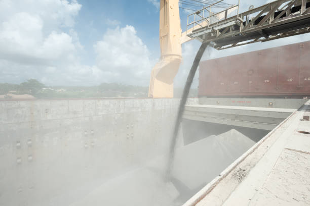 Loading of ship cargo gold with bulk cargo bauxite. Dusty atmosphere. Loading of ship cargo gold with bulk cargo bauxite using old vintage conveyer belt producing dust. guyana photos stock pictures, royalty-free photos & images