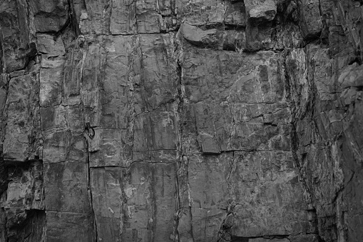 Black rock texture. Monochrome stone backdrop. Rough mountain surface. Close-up. Empty space. Dark gray grunge background.