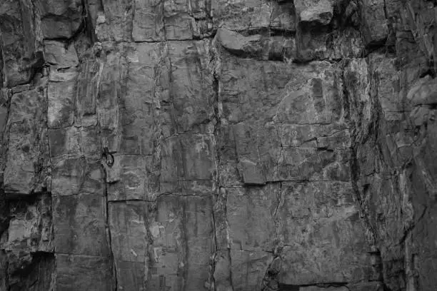 Photo of Black rock texture. Monochrome stone backdrop. Rough mountain surface. Close-up. Empty space.