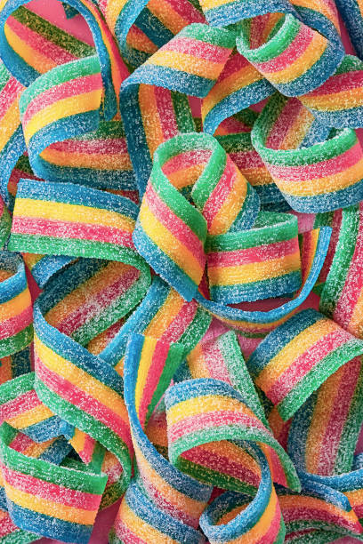 istock Colorful sugar candy ribbon on a pink background viewed from above. Top view. Full frame 1279475761