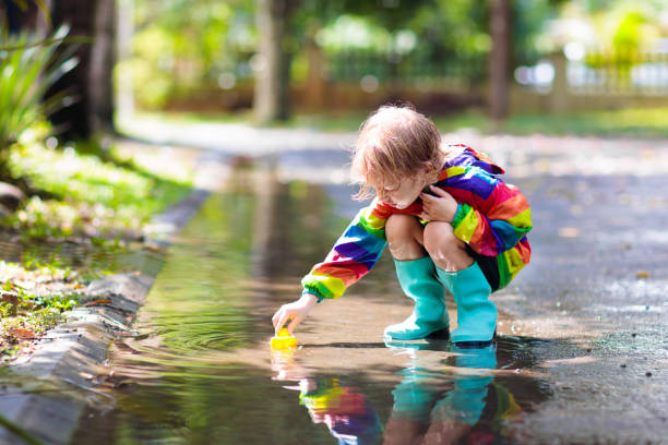 kinder in pfütze im herbstregen. wasserdichter verschleiß - puddle rain boot water stock-fotos und bilder