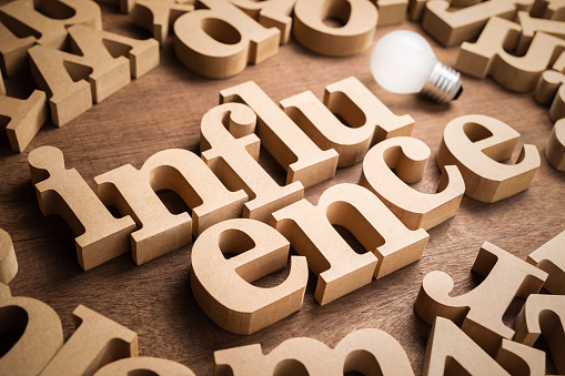 INFLUENCE wood word in scattered alphabets with glowing light bulb, matketing strategy concepet