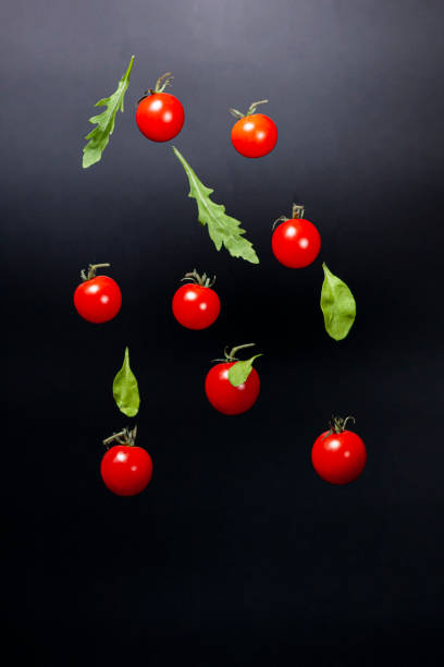 istock Red cherry tomatoes and leaves on a dark background. 1279483346