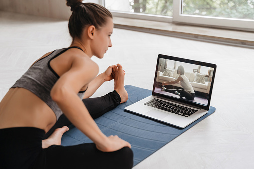 Mujer joven practicando yoga en casa en videoconferencia photo