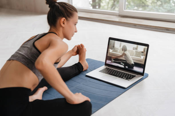 giovane donna che pratica yoga a casa in videoconferenza - yoga class instructor yoga exercising foto e immagini stock