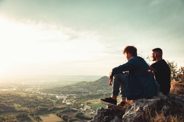 istock Young Men enjoying the Sunset View on Mountain Top Together 1279486931