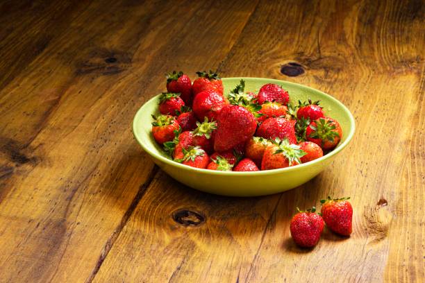 istock Strawberry in a green plate over rustic pine wood table 1279489292