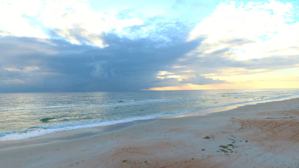 Ormond Beach at sunrise with colorful clouds sand and ocean