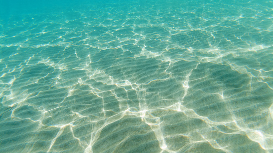 Underwater scene of beautiful turquoise Aegean sea with ripple water on the sand. Natural background. Selective focus