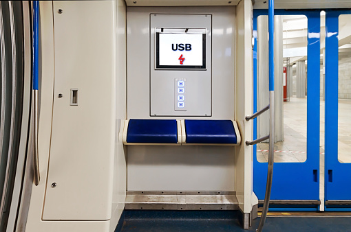 Usb charging system and TV or computer display and comfortable blue seats subway wagon train interior. Tech Device charge sharing and lifestyle concepts