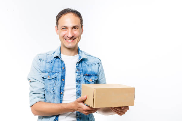 istock smiling delivery man holding a big parcel isolated on white 1279494560