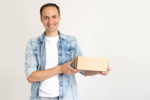 istock smiling delivery man holding a big parcel isolated on white 1279494617