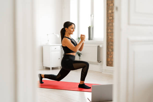 mujer haciendo estocadas mientras observa tutoriales de ejercicios - lunge fotografías e imágenes de stock