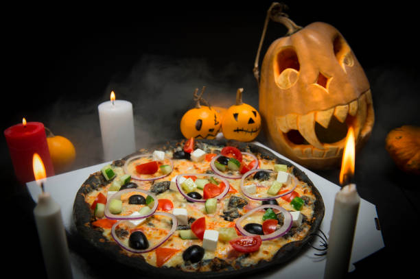 gemüsepizza in der nähe von halloween-dekoration: gruselige kürbisse mit bemalten gesichtern, lichter brennender kerzen in horrorrauch. - 7654 stock-fotos und bilder