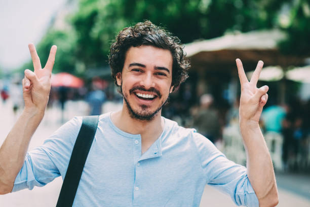 young man on the street waving his hand