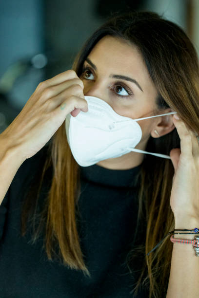 istock YOUNG WOMAN PUTTING ON HER PROTECTIVE MASK 1279505797