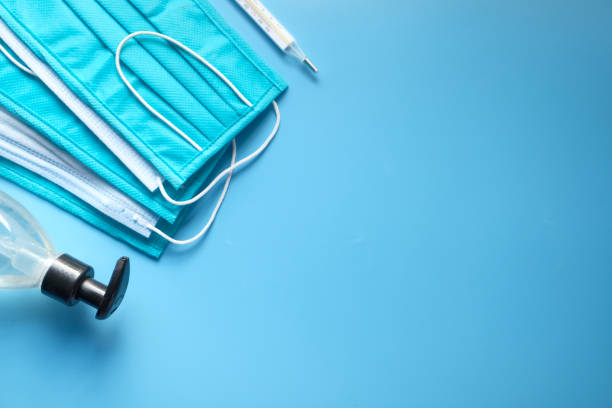 istock Surgical masks, thermometer and hand sanitizer on blue background 1279508725