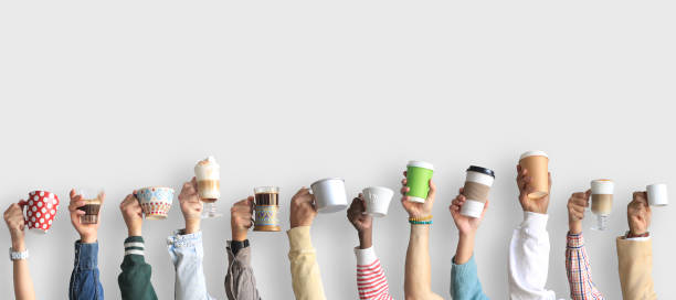 People are holding mugs and paper cups of coffee. stock photo
