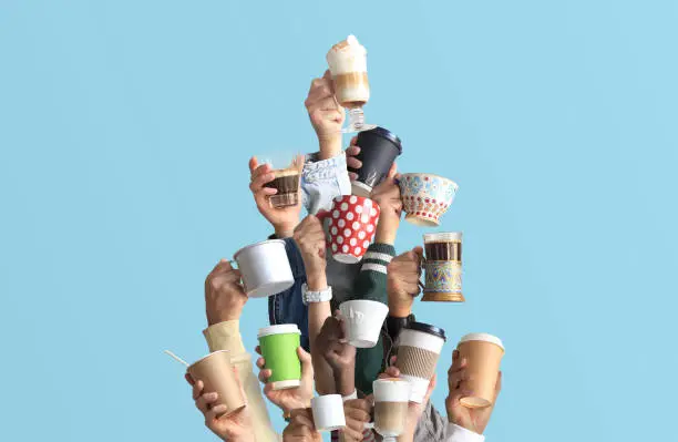 Photo of People are holding mugs and paper cups of coffee.