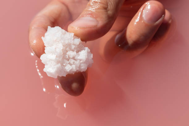 istock Hand holding salt crystal in pink water Nature spa 1279513954