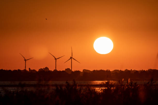 istock Energy wind power turbines, big sun on orange sky 1279514064