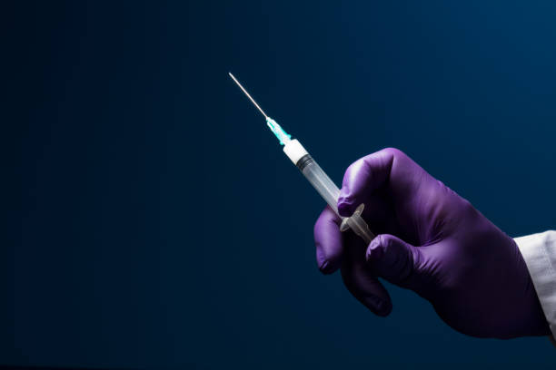 istock syringe in doctor's hand, blue background 1279517341