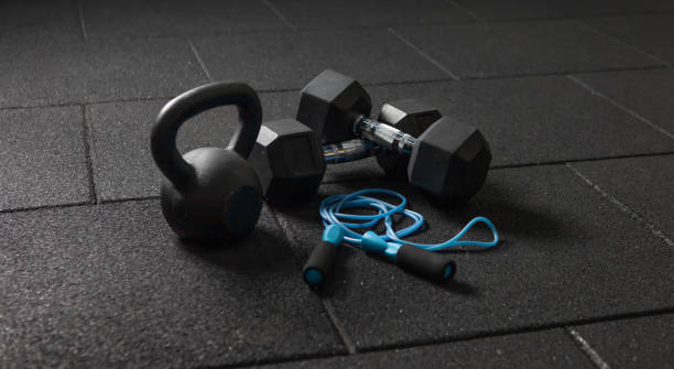 Functional training Sports equipment. Kettlebell and skipping rope, dumbbells on a dark black floor. Bodybuilding and fitness Functional training Sports equipment. Kettlebell and skipping rope, dumbbells on a dark black floor. Bodybuilding and fitness exercise equipment stock pictures, royalty-free photos & images