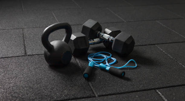 treinamento funcional equipamento esportivo. kettlebell e pular corda, halteres em um chão preto escuro. musculação e fitness - equipamento de ginástica - fotografias e filmes do acervo